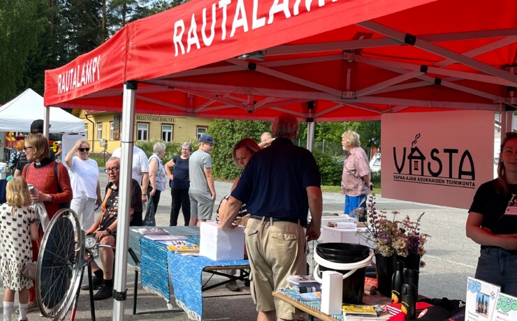 punainen telttakatos ja sen edessä ja takana ihmisiä kesätreffitapahtumassa Rautalammilla